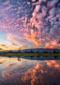 Captivating sunset with vibrant clouds and serene reflections over Pitt Meadows, BC.