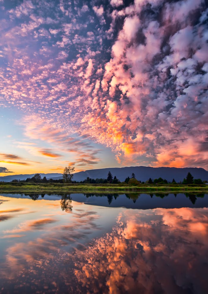 Captivating sunset with vibrant clouds and serene reflections over Pitt Meadows, BC.