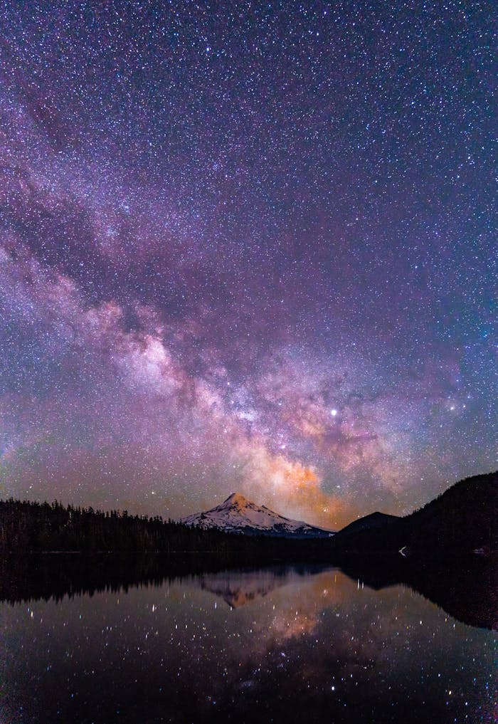 Capture of a brilliant starry night over a serene lake with a mountain peak reflection, creating a magical scene.