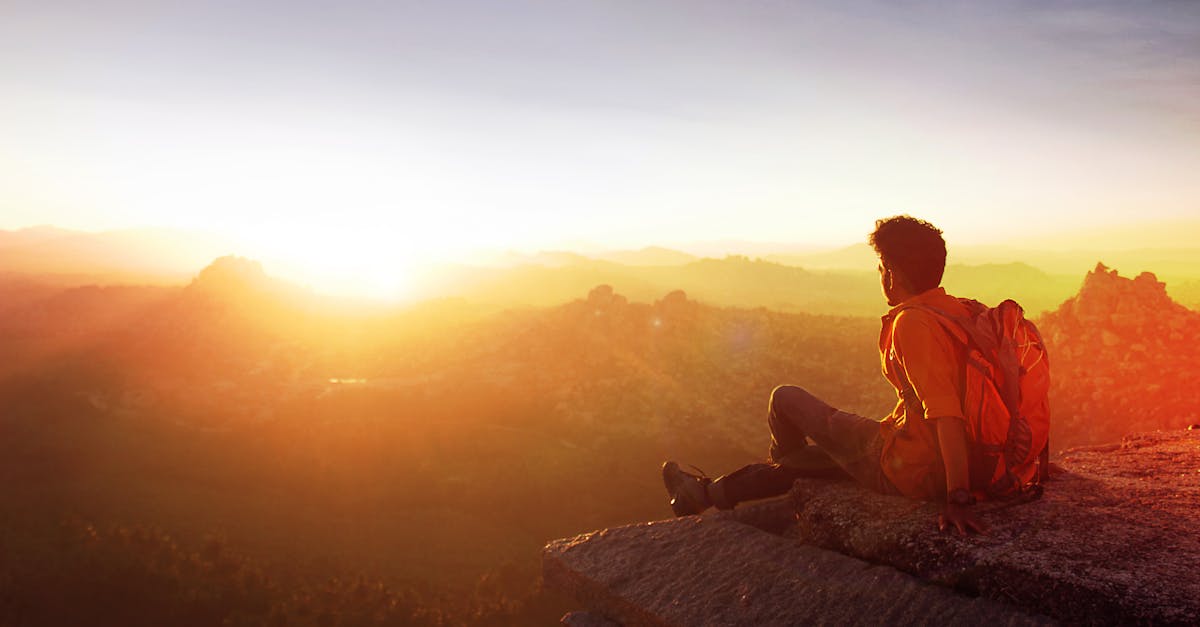 A man enjoys a breathtaking sunset view from a rocky cliff in Hampi, India.